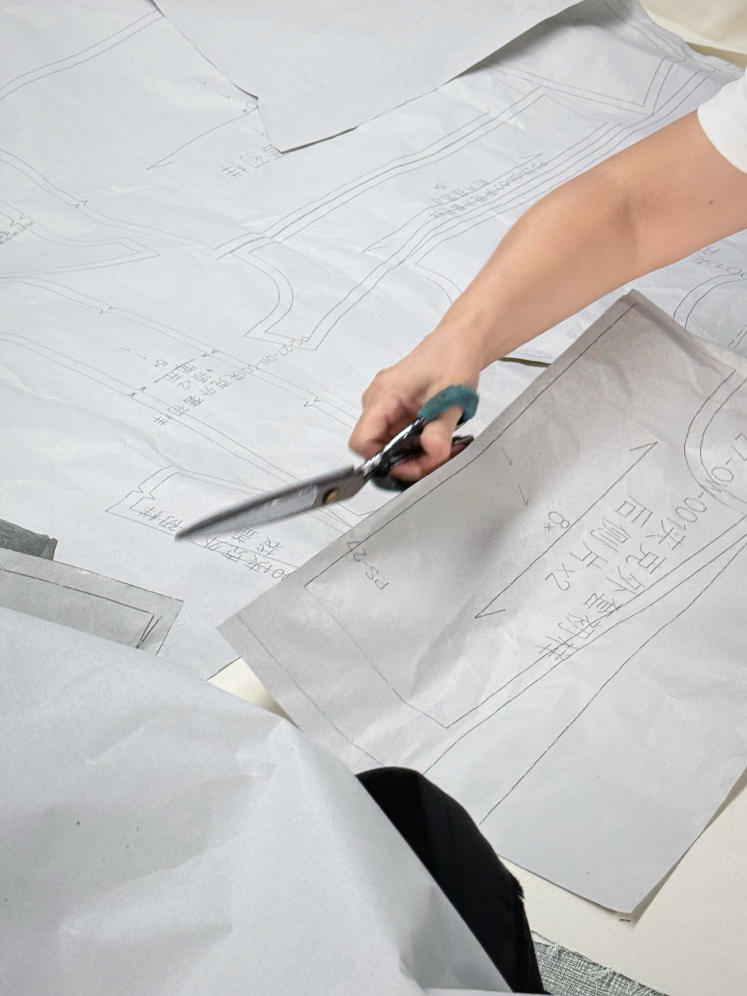 Pattern maker cutting a paper garment pattern by hand